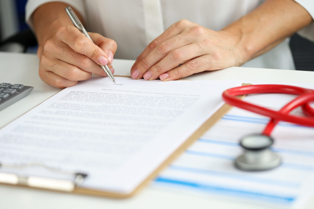 female doctor in medical gown put sign on clipboard with documents