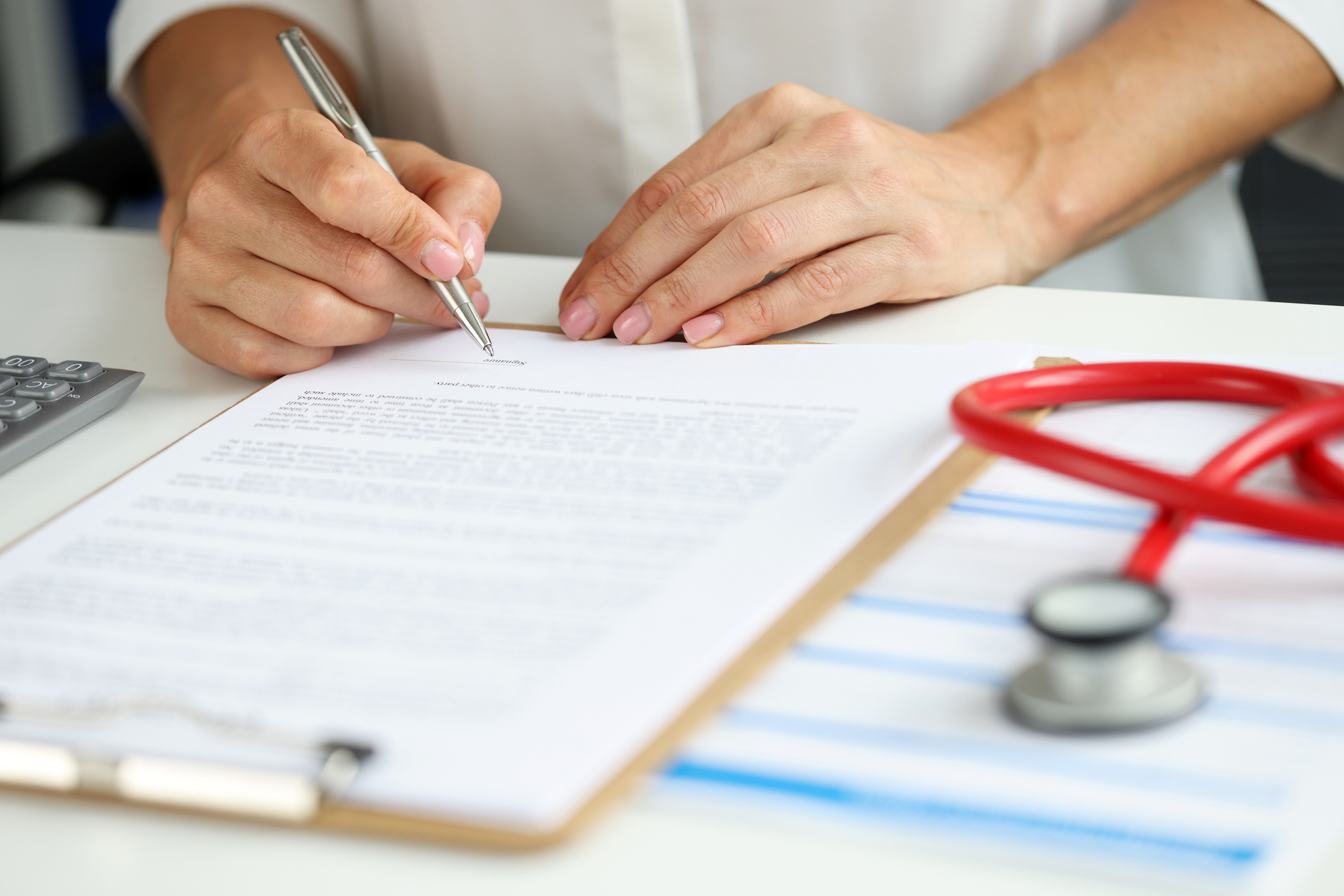 female doctor in medical gown put sign on clipboard with documents