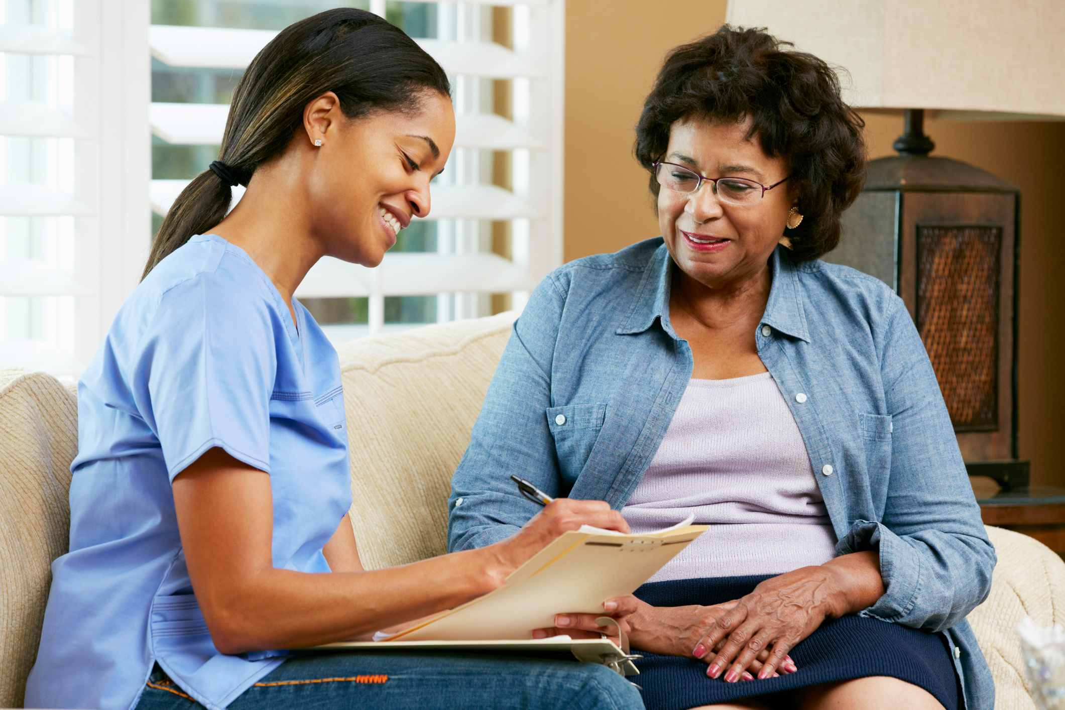 nurse making notes during home visit with senior patient